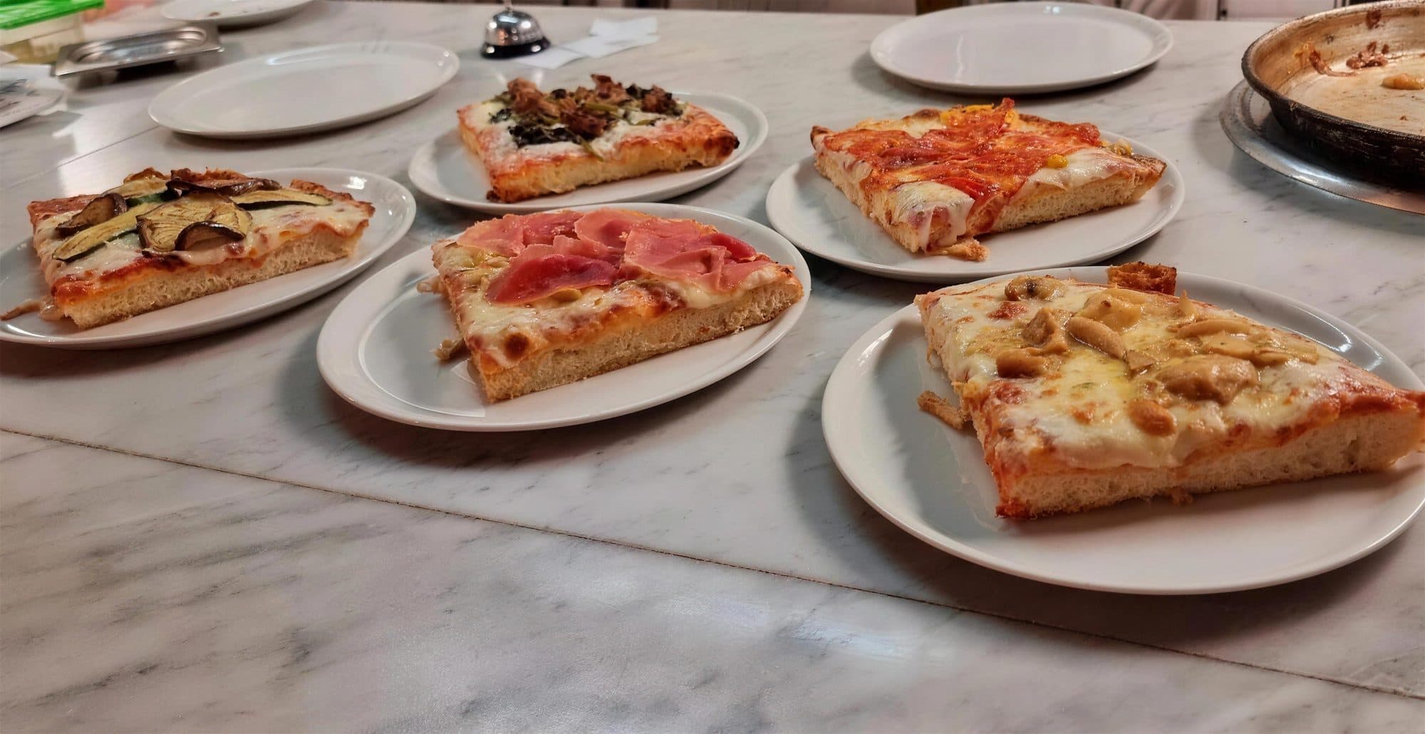 Pizza slices on the marble counter at Padellone