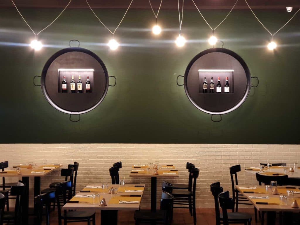 The Padellone dining room with the green wall, the two pans with the bottles and the string lights
